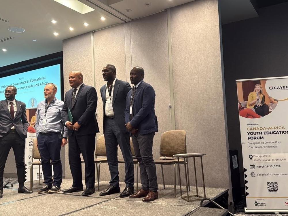 Cinq panélistes debout à l'avant d'une salle de conférence. Un écran derrière eux affiche « Panel 1 : Politiques et gouvernance des partenariats éducatifs entre le Canada et l'Afrique », et une bannière à droite annonce la deuxième édition du forum à l'hôtel Pantages, Toronto.